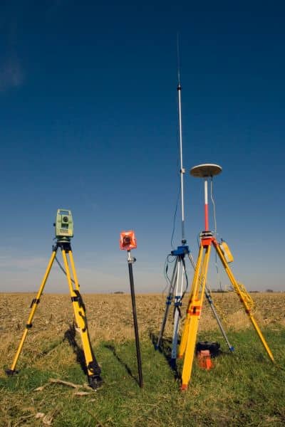 Surveying instruments including a total station and GNSS receiver set up on tripods, representing the technical precision behind every drone survey