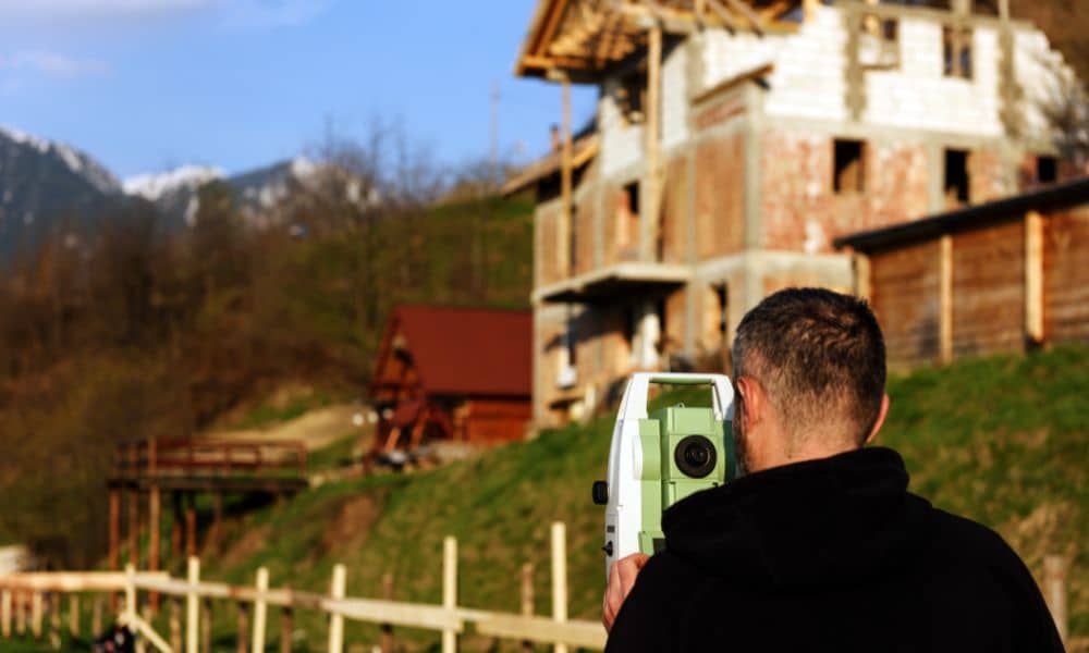 Land surveyor using total station equipment during a construction staking survey at a residential building site in Houston