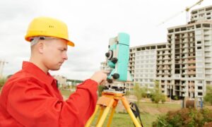 Surveyor in Houston using professional equipment for a topographic survey near a construction site
