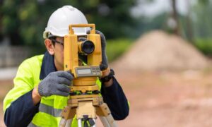 Licensed land surveyor using a total station to measure benchmarks and datums for an ALTA Land Title Survey