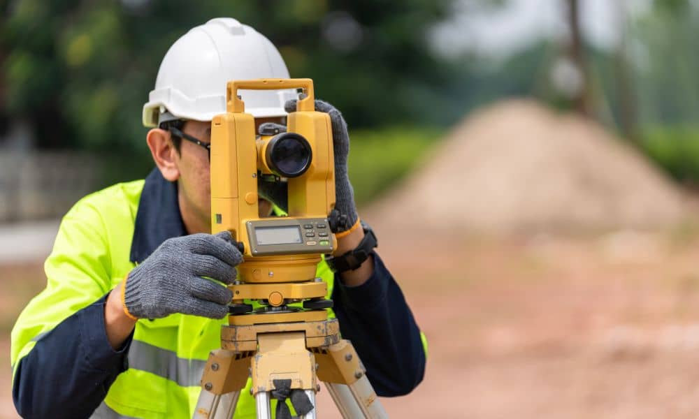 Licensed land surveyor using a total station to measure benchmarks and datums for an ALTA Land Title Survey