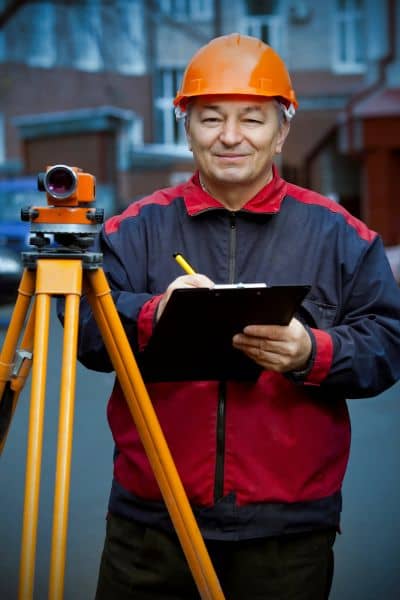 Licensed surveyor conducting a boundary line survey with equipment to clarify property lines and flood zone overlap
