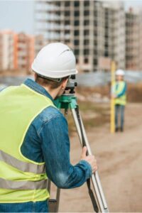 Licensed land surveyor in Houston using tripod to measure property elevation for an elevation certificate