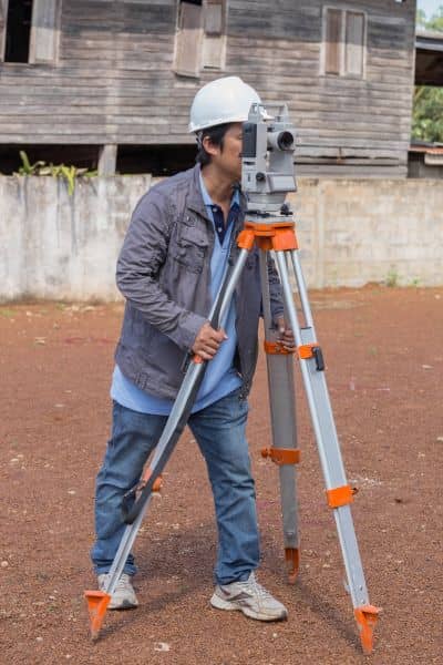 A surveyor using a total station to map a property line, showing how a property survey provides clear boundaries and prevents disputes