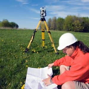 Licensed surveyor reviewing documents during a property line survey near a residential boundary