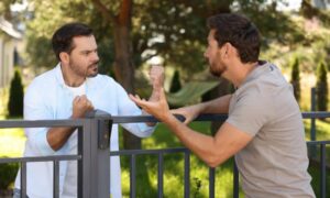 Two homeowners arguing over a fence during a property line survey dispute