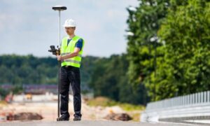 Surveyor conducting survey mapping with a GPS rover on an active construction site