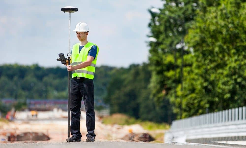 Surveyor conducting survey mapping with a GPS rover on an active construction site