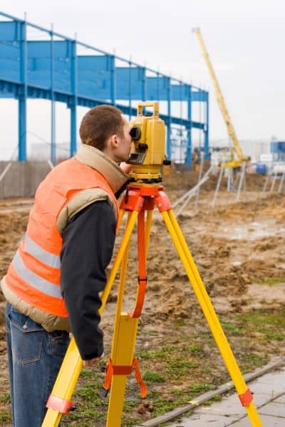 Surveyor using a total station on a construction site during a land survey to collect accurate measurements for planning