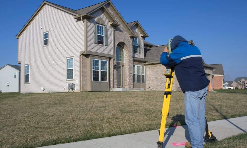 A licensed surveyor measuring a residential property to verify boundaries before construction
