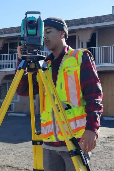 Construction surveyor using equipment to measure building layout and distances on a site